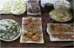 A table with various homemade dishes covered in plastic wrap.