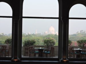 View of the Taj Mahal framed by a window with a table and chairs in the foreground.