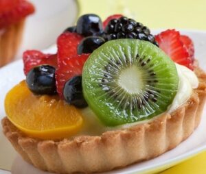 A fruit tart topped with kiwi, strawberries, blueberries, and apricots.