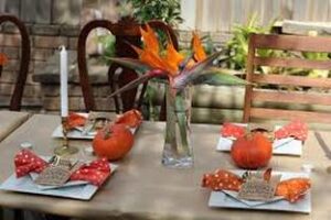 A cozy dining table with bird of paradise flowers and orange-themed decorations.