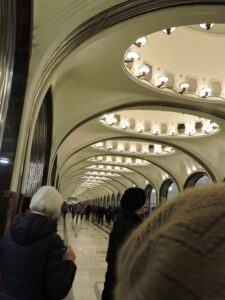 People waiting in a long, arched underground station corridor.