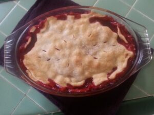 A freshly baked fruit pie with a golden crust in a black dish.