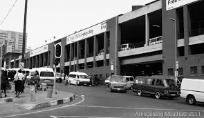 Black and white image of a busy urban street with vehicles and buildings.