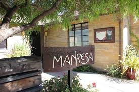 Signboard with 'Manresa' outside a rustic building surrounded by greenery.