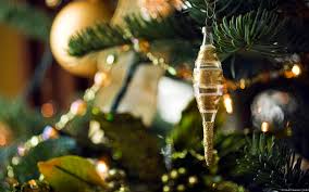 Close-up of a golden Christmas tree ornament hanging on a decorated tree.