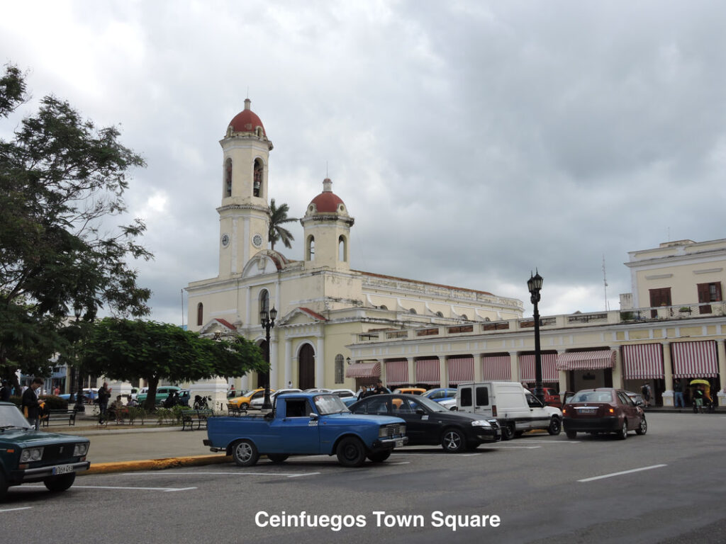 Coatepeque's town square with a church and classic cars under a cloudy sky.