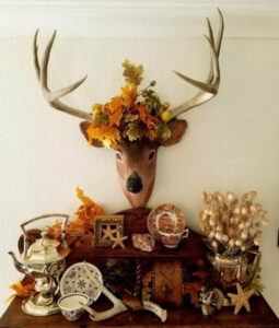 Decorative deer head with autumn flowers and rustic decor.