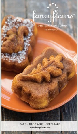 Decorative autumn-themed pastries topped with powdered sugar on an orange plate.