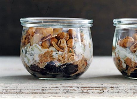 Layered dessert in a glass jar with nuts and chocolate.