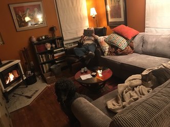 Cozy living room with a person relaxing on the couch and a dog nearby.