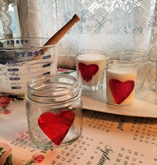 Glass jars decorated with red heart stickers on a table.