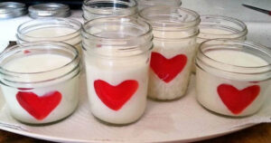 Jars filled with white candles, each adorned with a red heart.