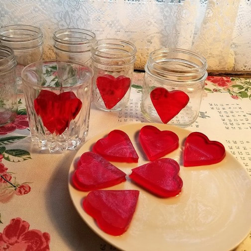 Red heart-shaped jelly desserts in glasses and on a plate.