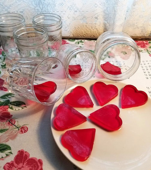 Heart-shaped red desserts in glass jars and on a plate.