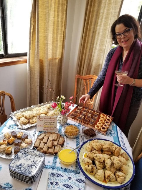 Woman standing by a table filled with assorted pastries and drinks.