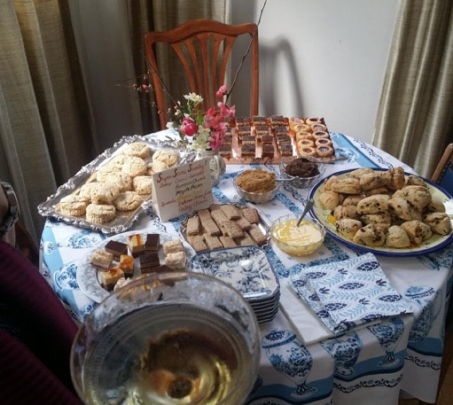Table set with various homemade pastries and a glass of white wine.