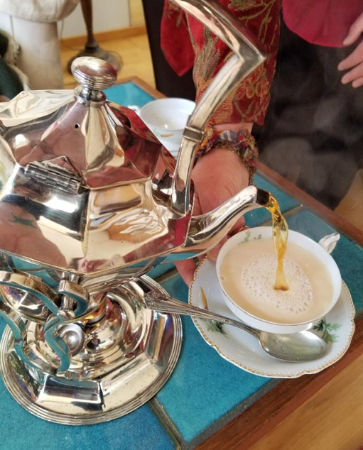 A teapot pouring tea into a cup with steam rising.