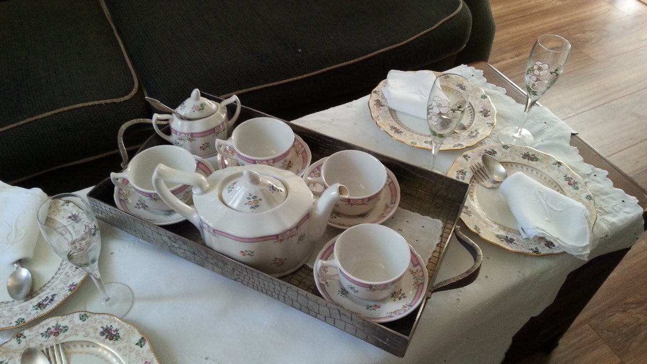 Elegant tea set with cups, saucers, and teapot on a wooden tray.