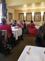 People dining in a cozy, warmly lit restaurant with framed artwork on walls.
