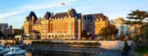 Historic grand hotel by the river under a clear sky.