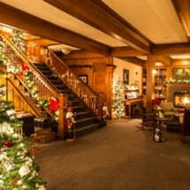Cozy Christmas-decorated lobby with wooden stairs and warm lighting.