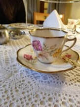 Elegant porcelain teacup and saucer with floral design on lace tablecloth.