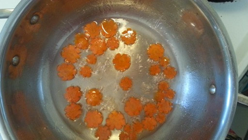 Orange carrot slices cooking in a pan.