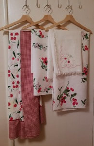 Set of floral and checkered patterned kitchen towels hanging on hooks.