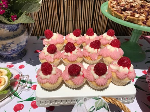 Pink raspberry cupcakes with white frosting arranged on a platter.