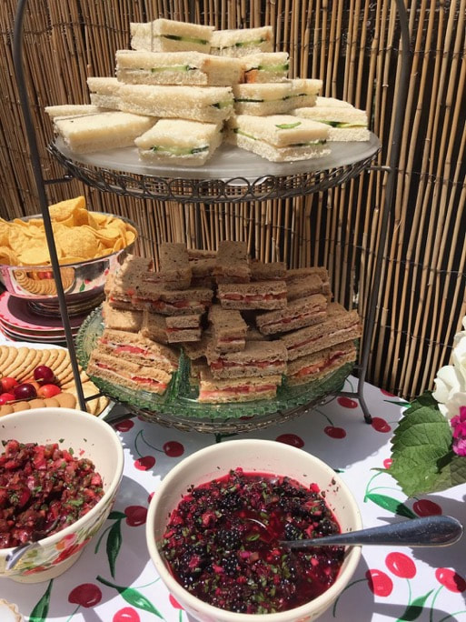 Tiered stand with assorted sandwiches and bowls of berries.