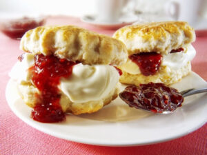 Scones filled with clotted cream and strawberry jam on a plate.