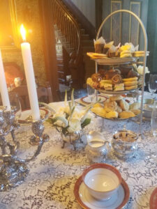 Elegant table setting with candles, flowers, and a tiered tray of assorted pastries and treats.