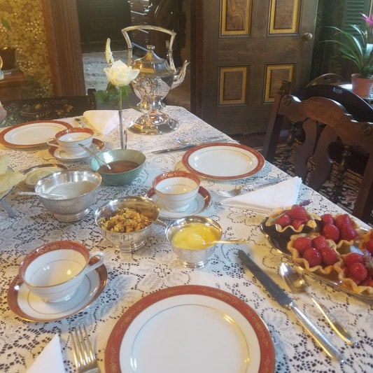 Elegant dining table set for a formal meal with fine china and desserts.