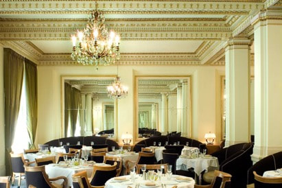 Elegant dining room with chandeliers and mirrors.