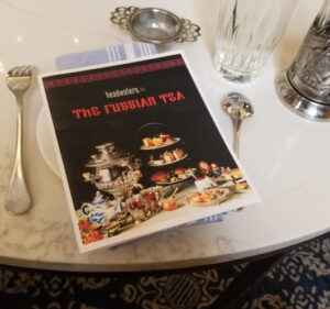 A book titled 'The Grand Tea' displayed on a table set for tea.