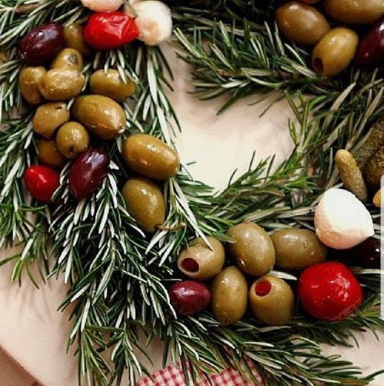A festive wreath made of rosemary, olives, cherry tomatoes, and garlic cloves.