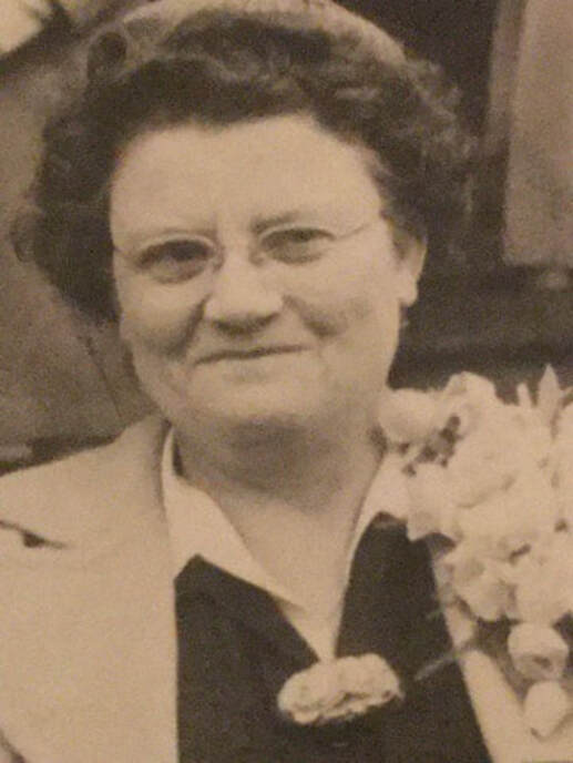 Black-and-white portrait of a smiling woman with glasses and curly hair.