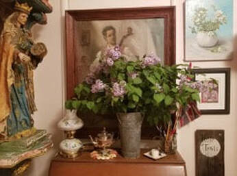 A cozy vintage room corner with flowers and framed pictures.
