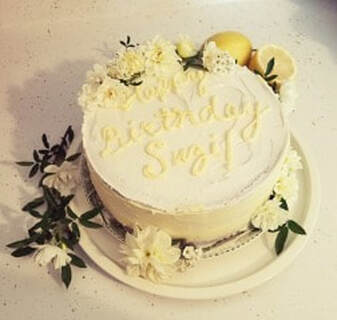 Elegant white cake decorated with flowers and 'Happy Birthday Suzy' inscription.