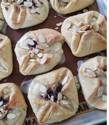 Freshly baked pastries with almond toppings on a baking sheet.