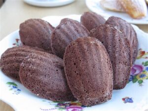 Close-up of freshly baked chocolate madeleines on a plate.