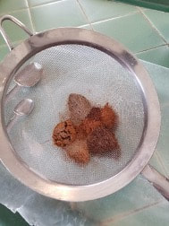 Metal sieve with white and brown powders inside.