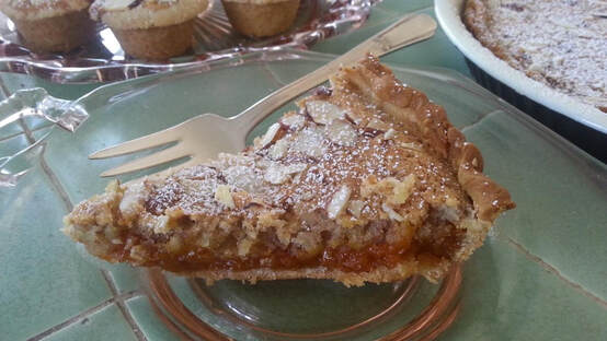 Slice of almond tart dusted with powdered sugar on a plate.