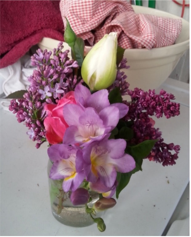 A colorful bouquet featuring pink, purple, and white flowers in a small container.