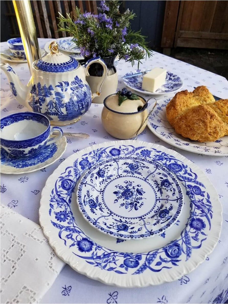 Blue and white china set with scones on a lace-covered table.