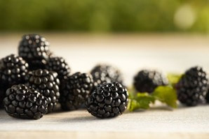 Close-up of fresh blackberries on a wooden surface.