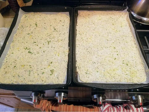 Two trays filled with uncooked herb and cheese casserole mixture.