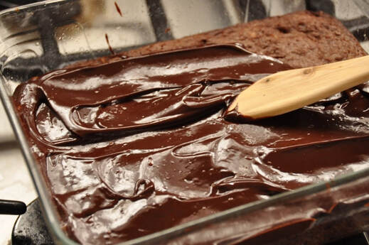 Smooth chocolate being spread with a wooden spatula.