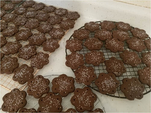 Homemade chocolate cookies arranged on a tray, some with a flower shape and others in a rectangular grid.