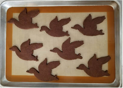 Chocolate bird-shaped cookies on a tray.
